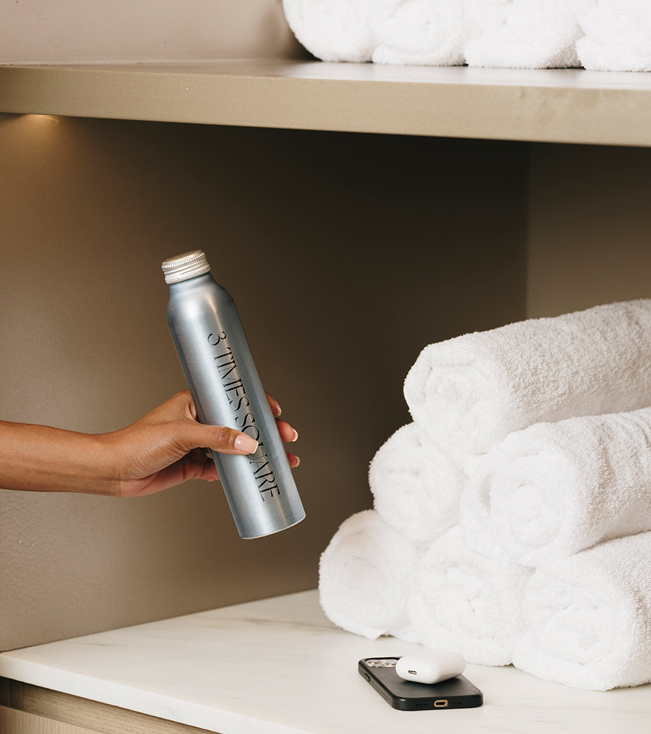 Person holding a water bottle with rolled towels and a phone in the background